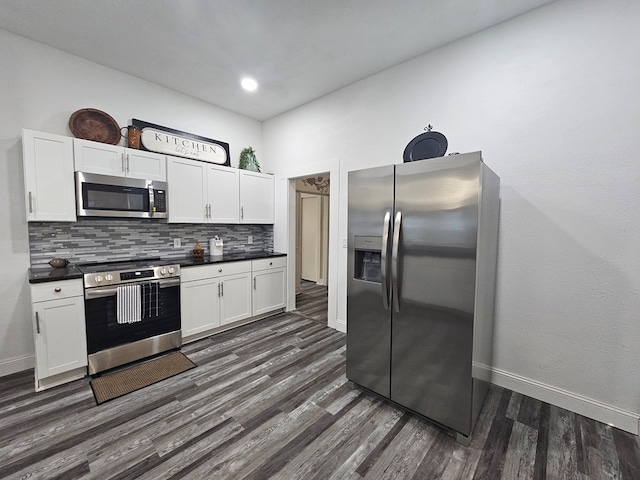 kitchen featuring dark countertops, dark wood-type flooring, decorative backsplash, stainless steel appliances, and white cabinetry