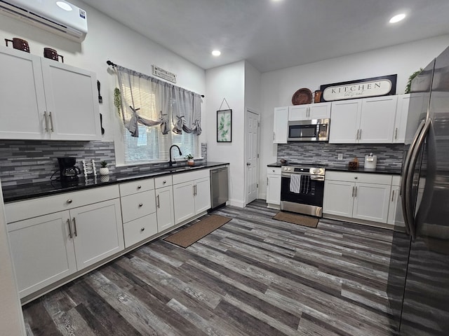 kitchen featuring dark countertops, appliances with stainless steel finishes, white cabinetry, and a wall unit AC