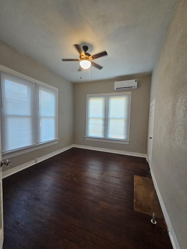 spare room featuring hardwood / wood-style flooring, baseboards, a wall mounted air conditioner, and ceiling fan