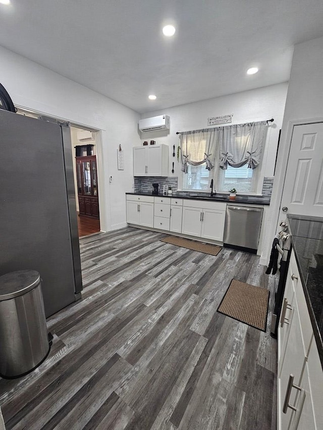 kitchen featuring a barn door, dark wood-type flooring, dark countertops, and stainless steel appliances