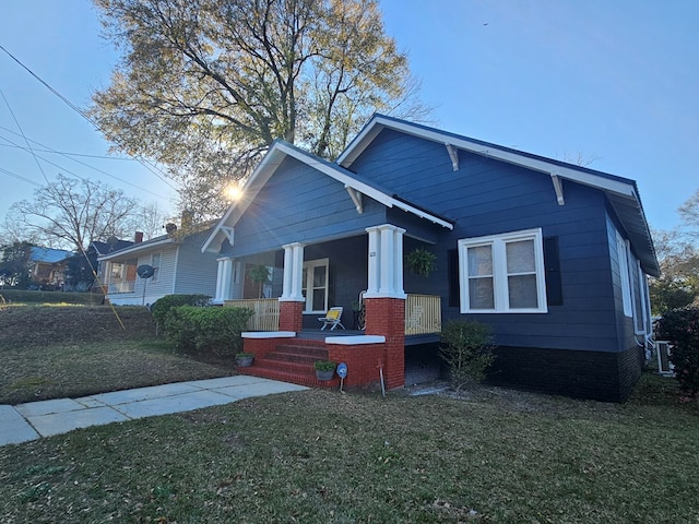 view of front of house featuring a porch, cooling unit, and a front lawn