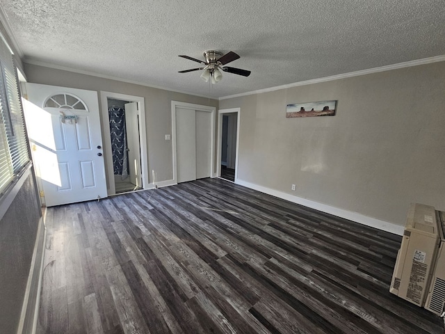 unfurnished living room featuring a textured ceiling, dark wood-type flooring, baseboards, and ornamental molding