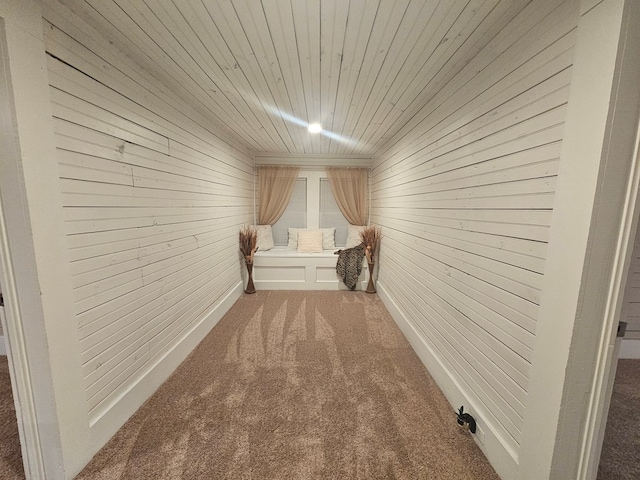 hallway with carpet, wood walls, and wooden ceiling