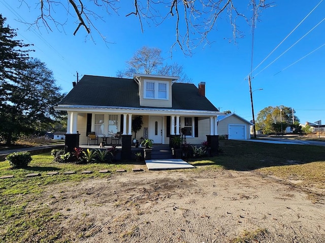 bungalow-style home featuring a garage, an outdoor structure, a front yard, and a porch