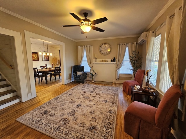 living area with an AC wall unit, wood-type flooring, ornamental molding, and ceiling fan