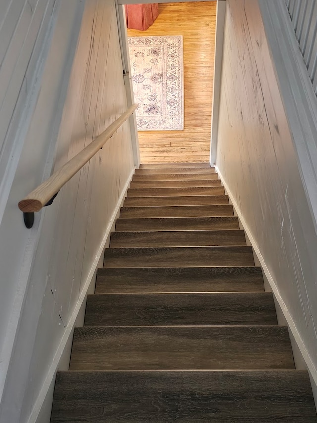 stairway featuring wooden walls