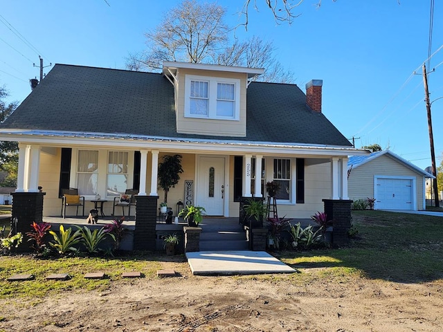 view of front of home with a porch, a garage, and an outbuilding