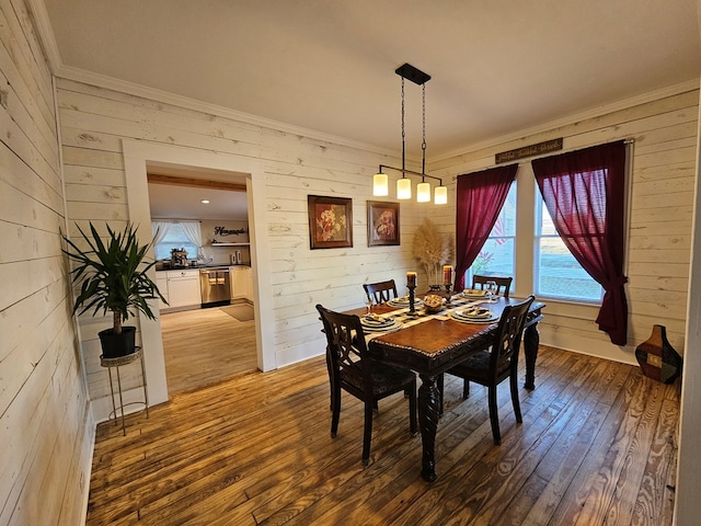 dining space featuring ornamental molding, hardwood / wood-style floors, and wooden walls