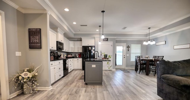 370 Airport Rd, Slocomb, AL 36375 - kitchen with black appliances, dark countertops, a center island with sink, a chandelier, and light wood-style floors