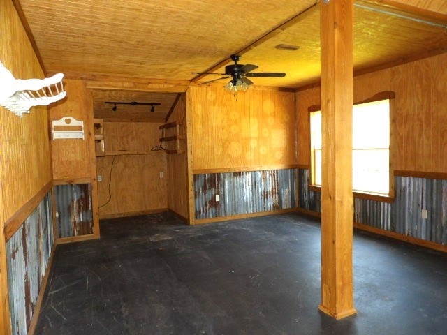 interior space with ceiling fan and wooden walls