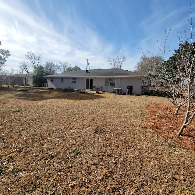 back of property featuring central air condition unit and a lawn