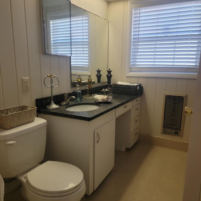 half bath with heating unit, toilet, and vanity