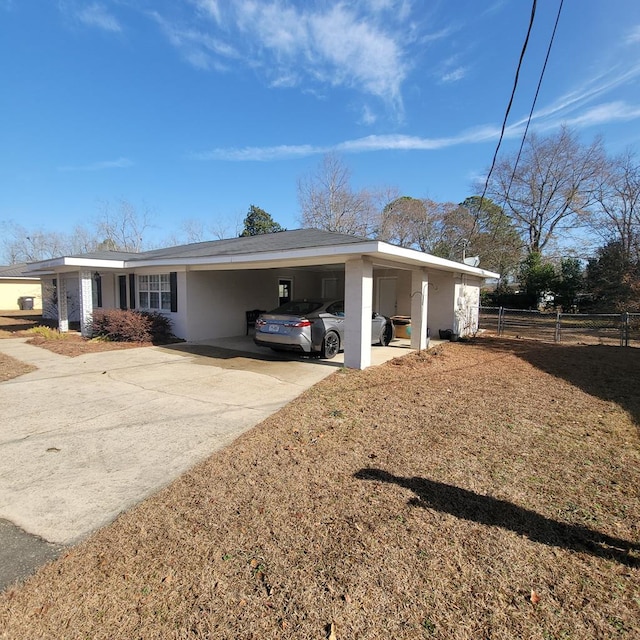 view of property exterior with a carport, fence, driveway, and stucco siding