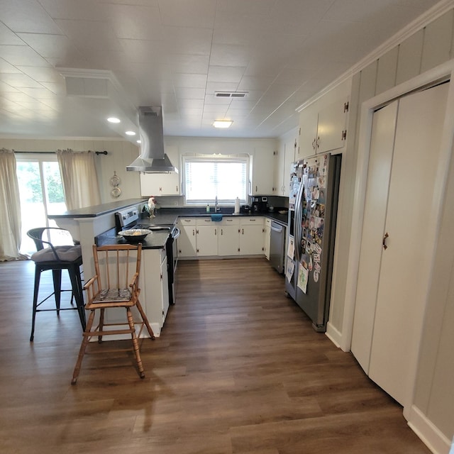 kitchen with dark countertops, dark wood-type flooring, stainless steel appliances, island range hood, and white cabinetry