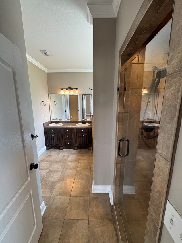 2103 Holland Rd, Newton, AL 36352 - bathroom with double vanity, crown molding, a shower stall, tile patterned flooring, and baseboards