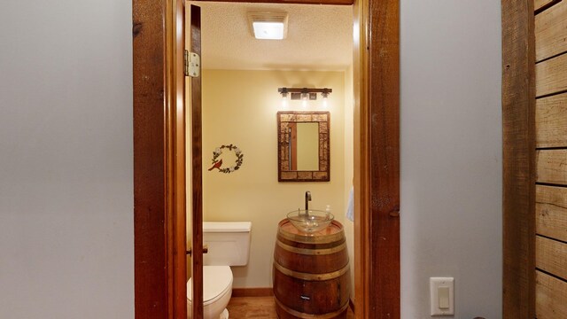 half bathroom with toilet, baseboards, and a textured ceiling