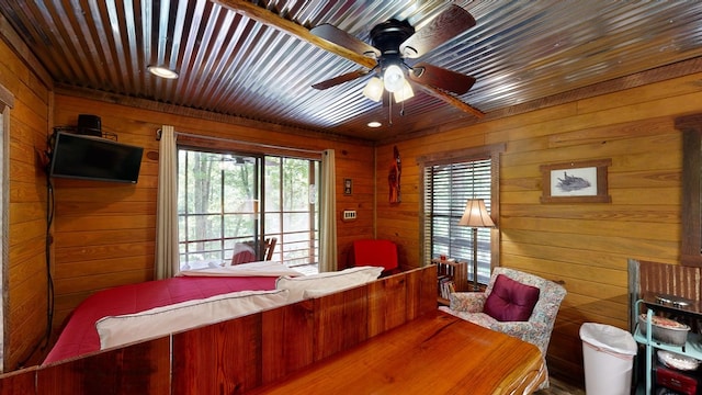 bedroom featuring ceiling fan, access to exterior, and wooden walls