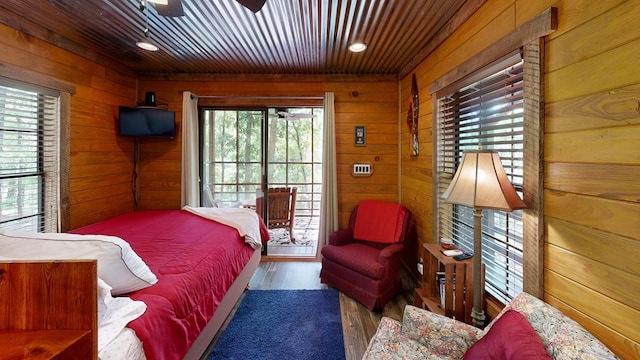 bedroom featuring access to exterior, wood ceiling, wood finished floors, and wood walls