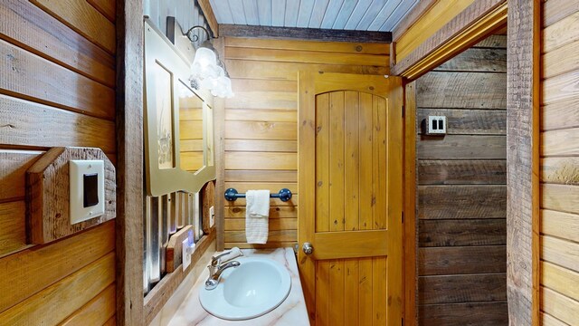 bathroom with sink, wood ceiling, and wooden walls