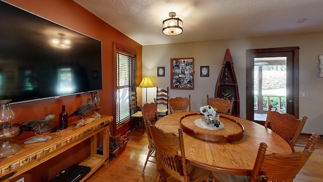 dining area featuring a textured ceiling, a wealth of natural light, and light hardwood / wood-style flooring