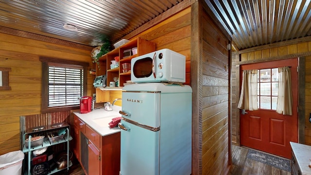 kitchen featuring plenty of natural light, fridge, wood walls, and sink