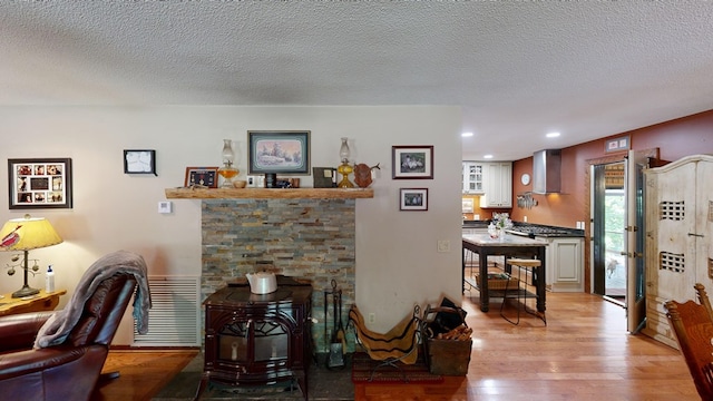 living room with visible vents, light wood-type flooring, recessed lighting, a wood stove, and a textured ceiling