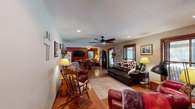 living room with ceiling fan, a textured ceiling, and hardwood / wood-style flooring