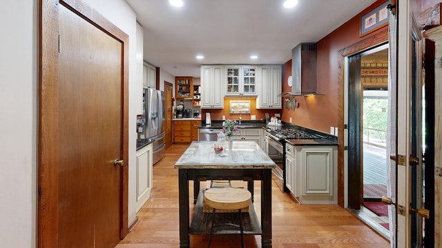 kitchen with sink, stainless steel appliances, light hardwood / wood-style flooring, and wall chimney exhaust hood