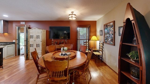 dining room with a textured ceiling, light hardwood / wood-style floors, and a healthy amount of sunlight