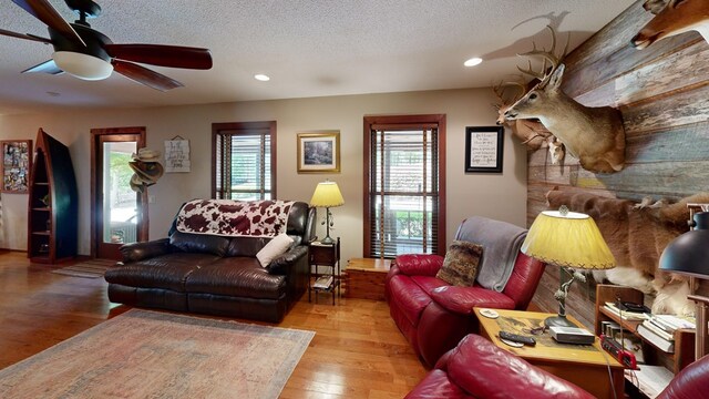 living room featuring light wood-type flooring, ceiling fan, a textured ceiling, and plenty of natural light