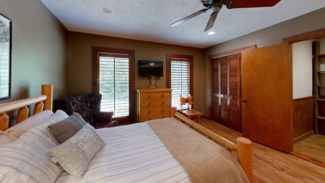 bedroom with ceiling fan, light wood-type flooring, a closet, and a textured ceiling