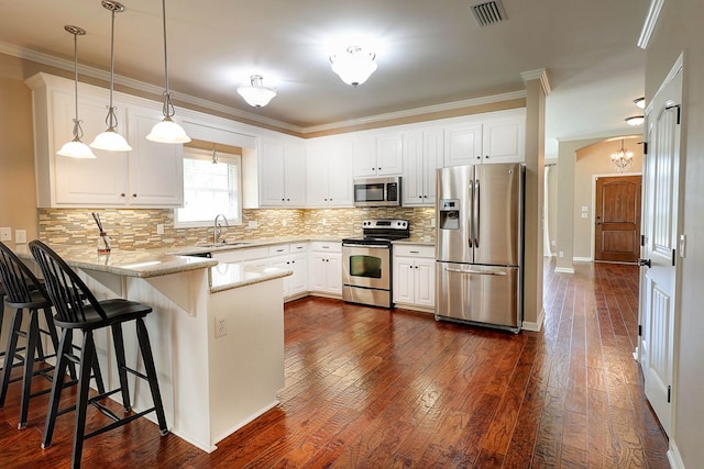 223 Veritas Dr, Dothan, AL 36303 - kitchen with stainless steel appliances, a peninsula, dark wood finished floors, decorative backsplash, and hanging light fixtures