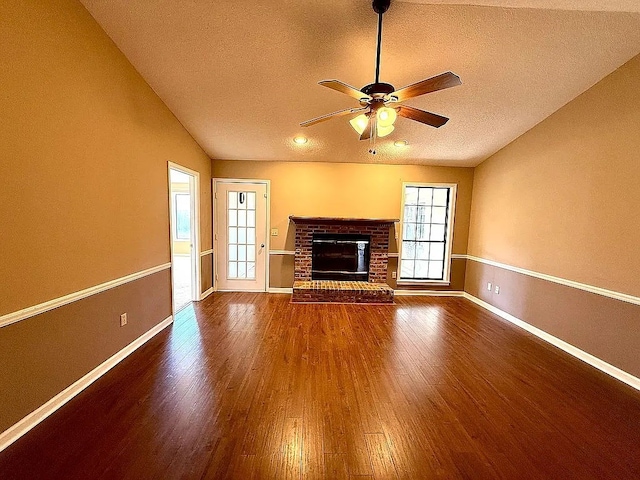 unfurnished living room with ceiling fan, wood-type flooring, vaulted ceiling, a textured ceiling, and a fireplace