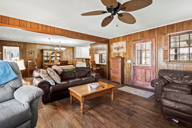 living room with ceiling fan with notable chandelier, a healthy amount of sunlight, dark wood-type flooring, and wooden walls