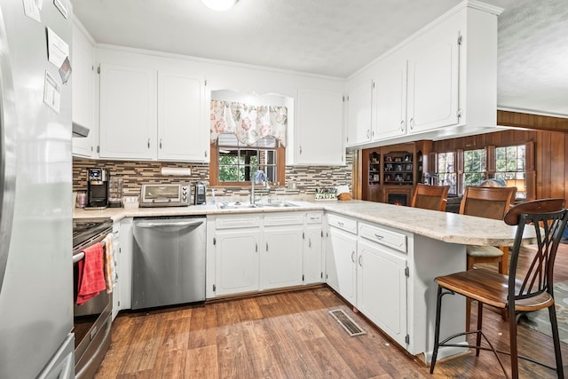 kitchen featuring sink, a breakfast bar, white cabinetry, stainless steel appliances, and kitchen peninsula