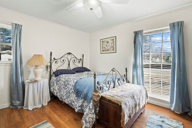 bedroom with ceiling fan, crown molding, multiple windows, and hardwood / wood-style floors