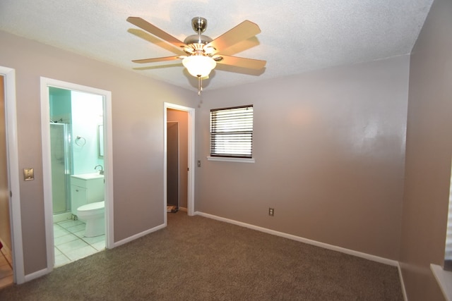 unfurnished bedroom featuring sink, ensuite bath, ceiling fan, carpet flooring, and a textured ceiling