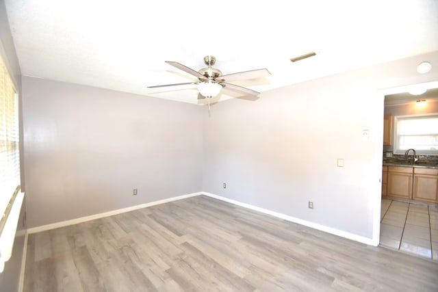 spare room with ceiling fan, sink, and light hardwood / wood-style flooring