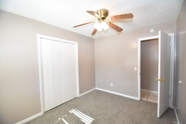 unfurnished bedroom featuring a textured ceiling, carpet floors, a closet, and ceiling fan