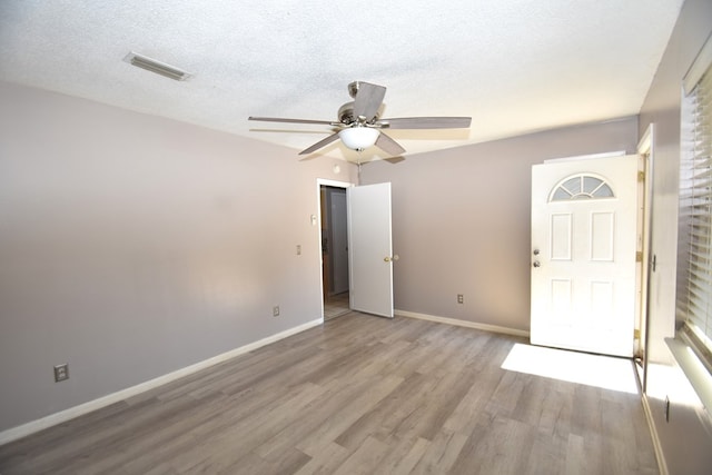 unfurnished room with ceiling fan, light hardwood / wood-style flooring, and a textured ceiling