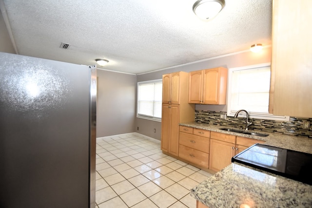 kitchen featuring light brown cabinetry, sink, stainless steel fridge, light tile patterned floors, and light stone counters