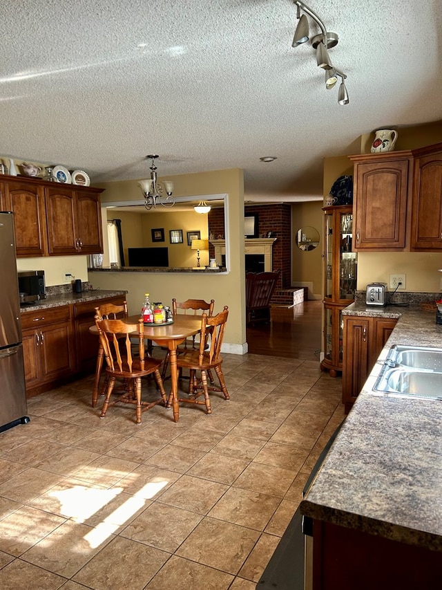 kitchen with sink, a textured ceiling, appliances with stainless steel finishes, and a brick fireplace