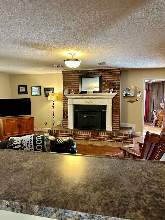 living room featuring a textured ceiling and a brick fireplace