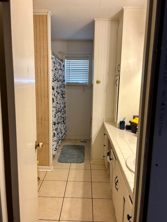 bathroom featuring vanity, tile patterned floors, crown molding, and wood walls