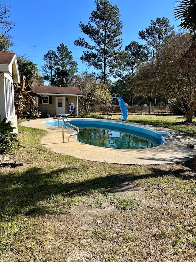 view of pool with an outbuilding, a lawn, and a water slide