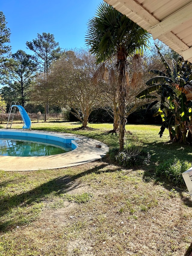 view of swimming pool with a lawn and a water slide