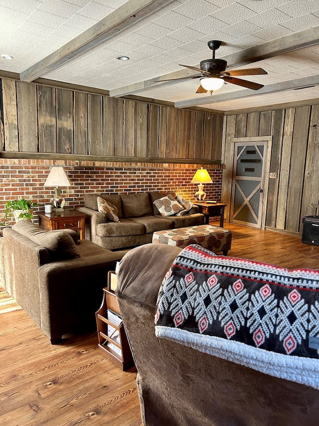 living room featuring wooden walls, light hardwood / wood-style floors, beamed ceiling, and brick wall