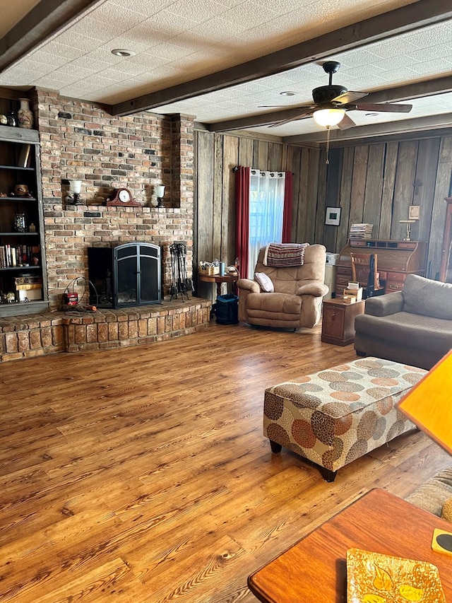 living room with hardwood / wood-style floors, a textured ceiling, ceiling fan, and wood walls