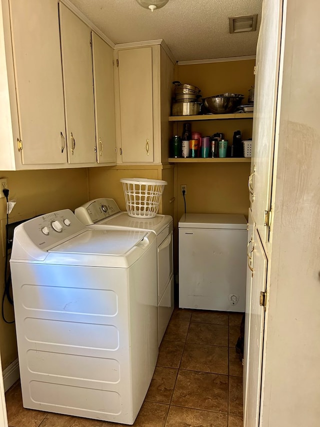 laundry room with washer and clothes dryer, cabinets, dark tile patterned floors, and a textured ceiling