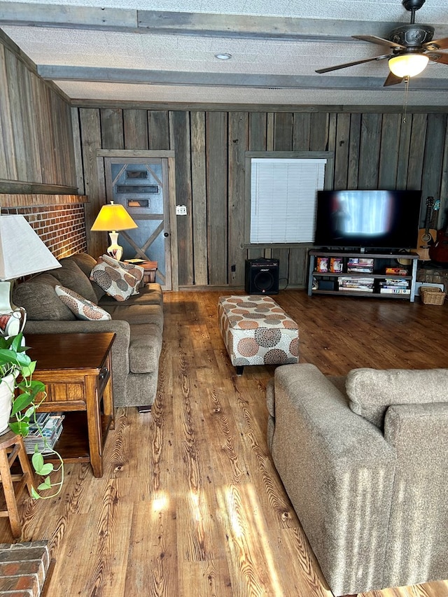 living room featuring a textured ceiling, light hardwood / wood-style flooring, ceiling fan, and wooden walls